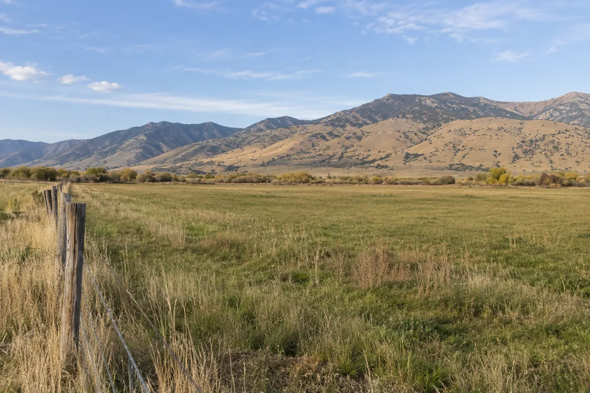 Open pasture beside a weathered fence with dry Utah mountain foothills beyond