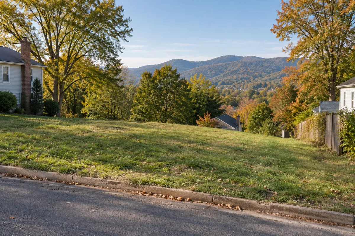 Open grassy lot beside a street with wooded hills beyond